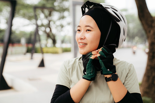 Muslim Woman putting on helmet  on the park