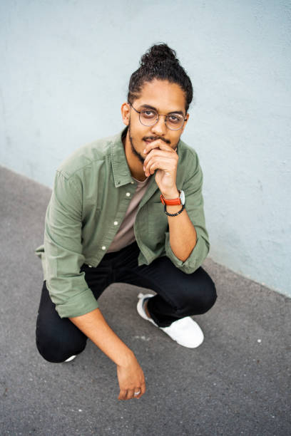 istock Cool young man crouching on a city sidewalk 1415956409
