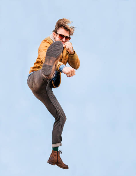 istock Stylish young man drop kicking in mid air on a blue background 1415956456