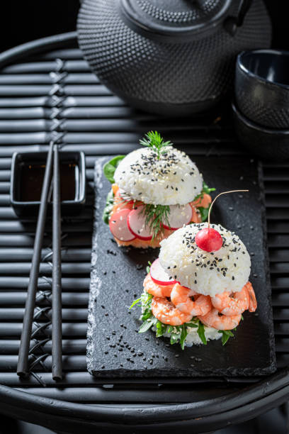 istock Exquisite sushi burger with shrimps and fish on strone plate. 1415957390