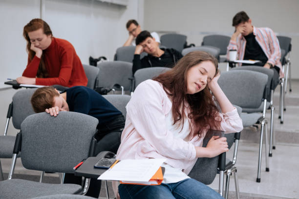 A lazy student sleeps on a desk during a boring lecture at a university or college. Fatigue from classes A lazy student sleeps on a desk during a boring lecture at a university or college. Fatigue from classes. male college student sleeping through lecture stock pictures, royalty-free photos & images