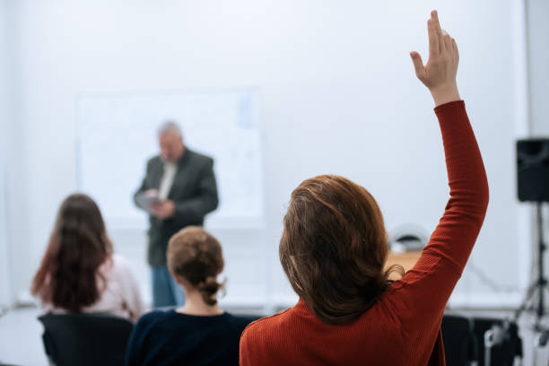 A famous professor has arrived at the university to conduct a special lesson, the student pulls his hand up to ask him a question stock photo