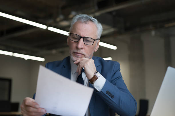 Portrait of successful banker holding financial report, analyzing documents at workplace stock photo