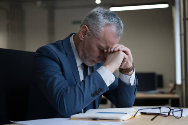 Tired stressed businessman sitting in office, failure business. Overwork concept stock photo