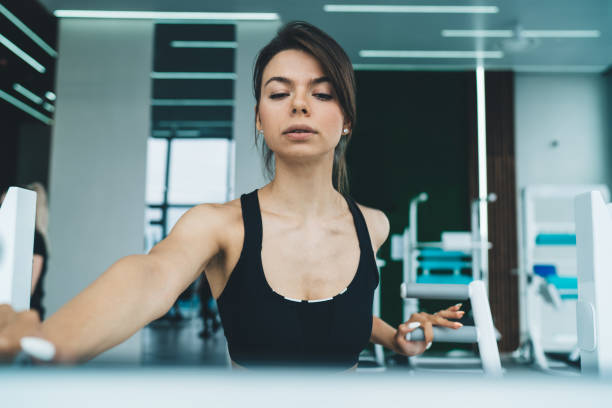 istock Beautiful brunette in active wear using equipment for training in gym enjoying slimming and healthy lifestyle, serious female with perfect body shape concentrated on workout for reaching goals 1415965796