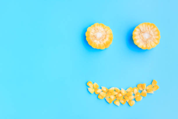 istock Yellow corn cob slice and seeds on blue background, Smile face 1415967711