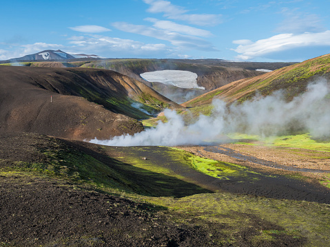 Landmannalaugar colorful Rhyolit mountains with steam from hot spring on famous Laugavegur trek. Fjallabak Nature Reserve in Highlands of Iceland, summer blue sky