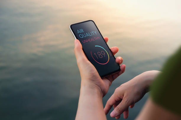 istock Air Pollution, Weather and Environment Issue Concept. Woman Using Mobile Phone to Check Air Quality as Unhealthy at the Riverside. Top View 1415971764