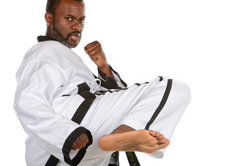 Close up Taekwondo martial arts fighter in white uniform two hands holding black belt on dark background