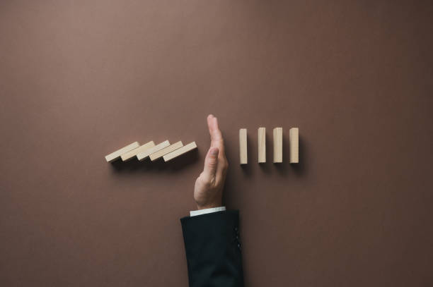 istock Hand of a businessman stopping falling dominos 1415972731