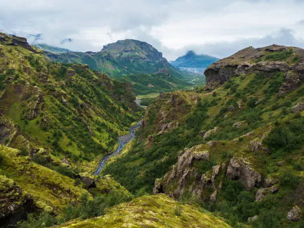 Photo of Landscape of Godland and thorsmork with rugged green moss covered rocks and hills, bending river canyon, Iceland, Fimmvorduhals hiking trail. Summer cloudy day.