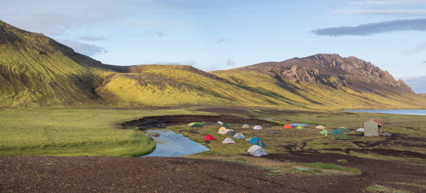 Panoramic landscape with colorful tents at camping site on blue Alftavatn lake with green hills and glacier in beautiful landscape of the Fjallabak Nature Reserve in the Highlands of Iceland, part of Laugavegur hiking trail paisaje panorámico con coloridas tiendas de campaña en el camping en el lago azul alftavatn con verdes colinas y glaciares en el hermoso paisaje de la reserva natural de fjallabak en las tierras altas de islandia parte de la ruta de senderismo laugavegur