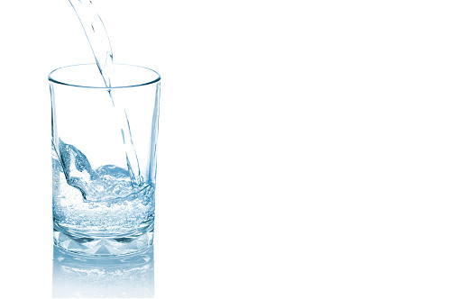 Pouring mineral water into clear glass isolated on white background.