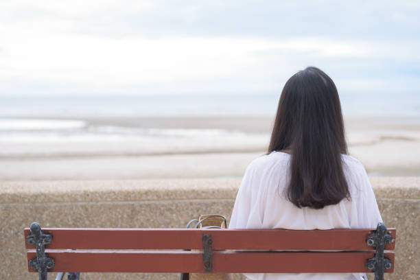 vue arrière d’une femme asiatique assise seule sur un banc de plage. - rear view women back back of head photos et images de collection