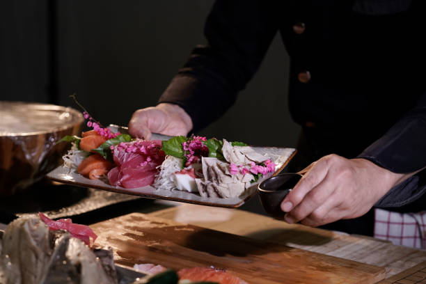 gros plan d’un chef japonais se préparant à cuisiner des plats japonais. faites des sushis dans un restaurant japonais traditionnel sur une planche à découper. - buffet thai cuisine asian ethnicity food photos et images de collection