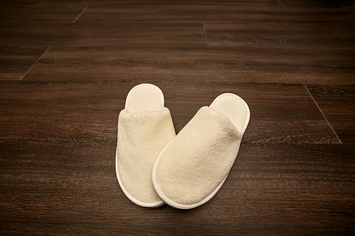 pair soft white slippers on wooden floor