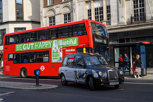 London, UK - Aug 14, 2023: Iconic, classic red double decker bus driving, turning on intersection with people sitting, eating during Afternoon Tea Tour
