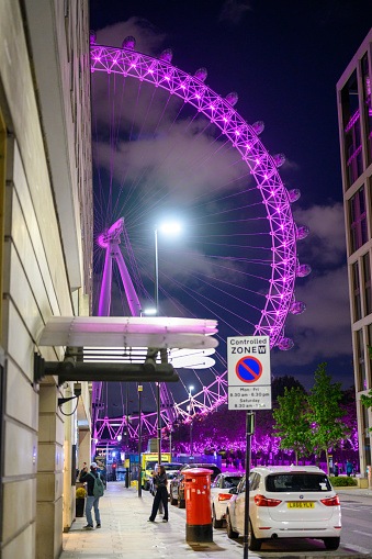 LONDON - May 17, 2022: London Eye illuminated purple next to County Hall Apartments at night