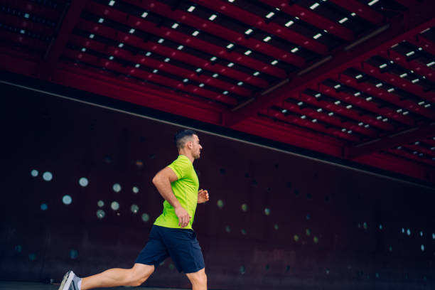istock Side view of determined male runner sprinting during cardio training at urban setting, Caucasian man enjoying stamina exercising during warm up concentration on leisure for practice physical intensity 1415984433