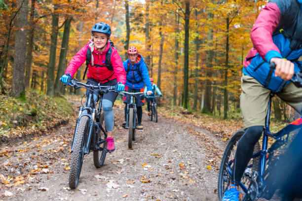 istock Group of cyclist riding on path in deciduous wood 1415985265