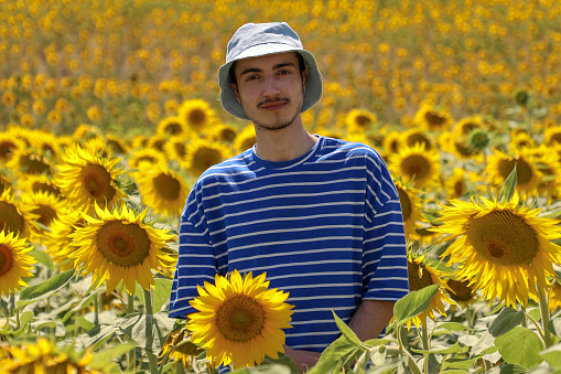 A young man wearing a hat on his head in a field of sunflowers