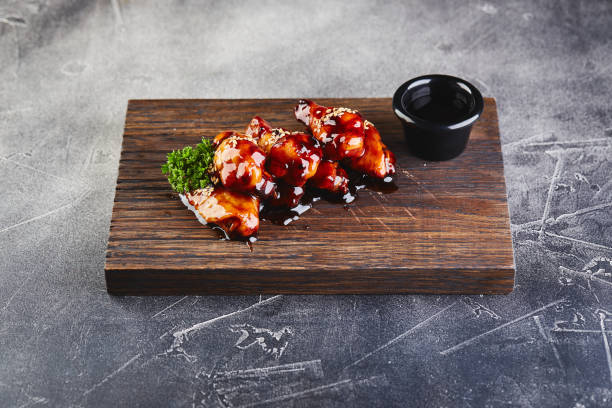 Chicken wings in teriyaki sauce on wooden cutting board Chicken wings in teriyaki sauce on wooden cutting board. sticky sesame chicken sauces stock pictures, royalty-free photos & images