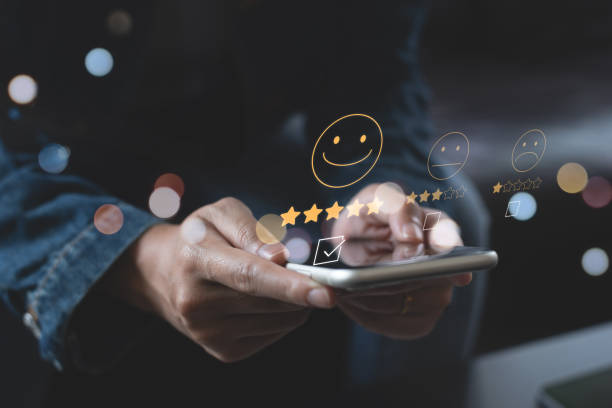 istock Woman pressing face emoticon on virtual touch screen on mobile smart phone. Customer review, service evaluation concept 1415991419