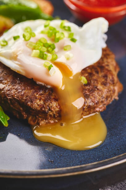 istock Minced beef steak with poached egg and vegetable garnish with tomato sauce on plate 1415992530