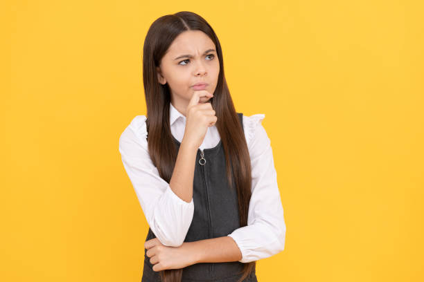 istock Thoughtful primary school child keep thinking yellow background, educated 1415994270