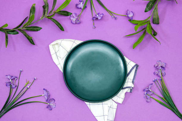 istock empty ceramic blue plate on purple background with beautiful flowers 1415994442