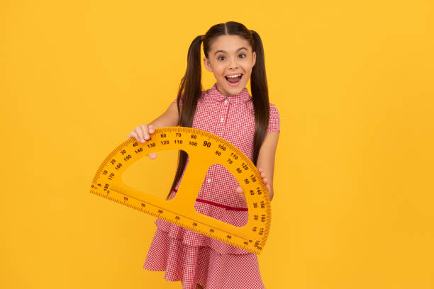 istock amazed kid hold school math tool protractor ruler on yellow background, school 1415995947