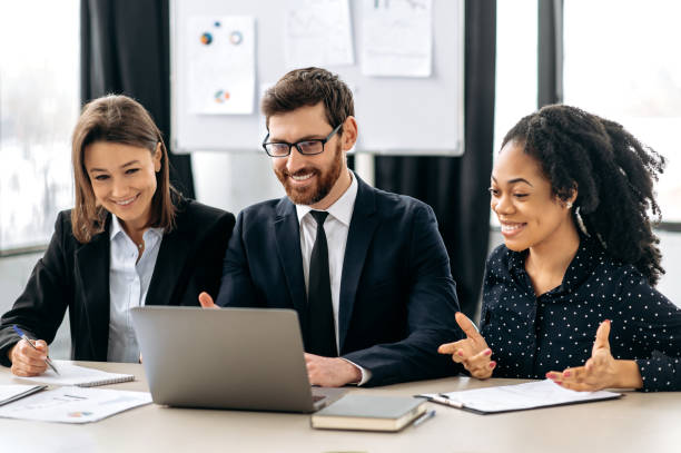 istock Multiracial colleagues are brainstorming on strategy together, sitting in modern office, studying documents, using laptop, discussing, smile. Successful creative business partners working on a project 1415996097