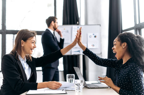 istock Two successful multi-ethnic female colleagues work in a modern office on a project, give each other five, rejoice at a successful deal, good profit, a successful startup, smiling. Agreement, deal 1415996123
