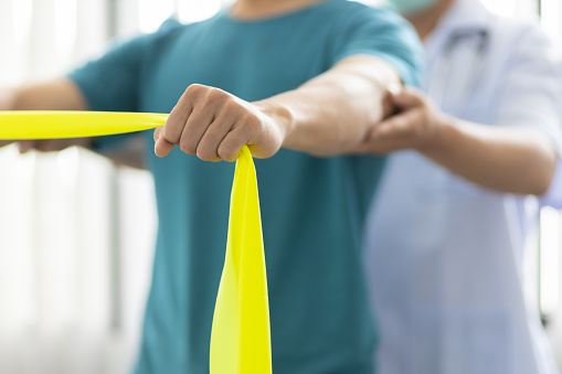 Physical therapists treat patients with exercises using latex therapy resistance band. Concept of physical therapy and rehabilitation.