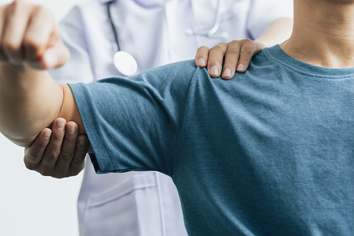 Un hombre con dolor de hombro va al médico, el médico diagnostica el dolor de brazo y el dolor de hombro del paciente. Concepto de fisioterapia y rehabilitación. photo