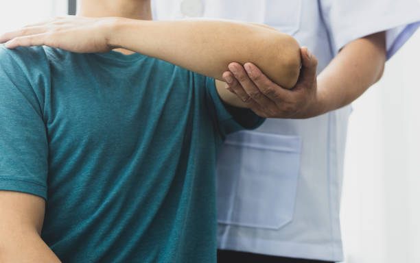 肩の痛みを持つ男性は医者に行きます, 医師は、患者の腕の痛みと肩の痛みを診断します.理学療法とリハビリテーションの概念。 - pain elbow physical therapy inflammation ストックフォトと画像