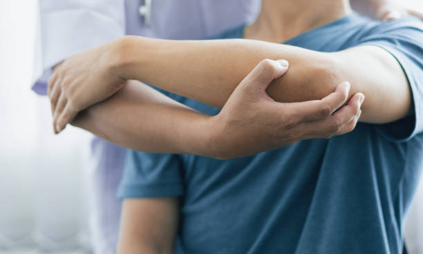 理学療法とリハビリテーションの概念。肩の痛みを持つ男性は医者に行きます, 医師は、患者の腕の痛みと肩の痛みを診断します. - pain elbow physical therapy inflammation ストックフォトと画像