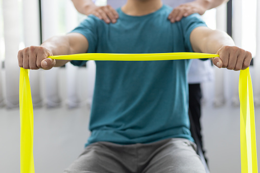 Physical therapists treat patients with exercises using latex therapy resistance band. Concept of physical therapy and rehabilitation.