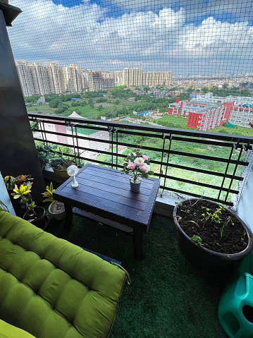 Stock photo of apartment balcony in Ghaziabad, India decorated with potted plants and artificial green grass turf. Gardening and exterior design concept.