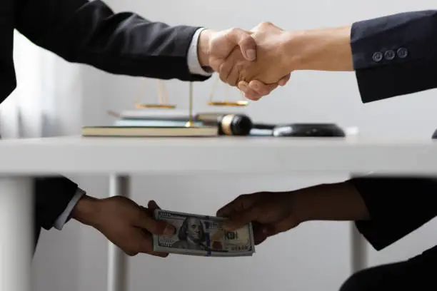 Photo of Business people shaking hands and Give an under-the-table bribe to an attorney to help a lawyer win a court case. Bribery and Kickback Ideas Fraud and Fraud