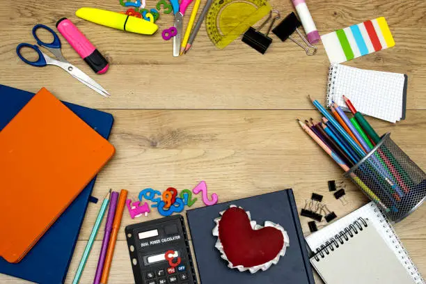 Back to school concept - pencil-box and books, notebooks and sticky note and calculator with pins, felt pen and heart shape on wooden table