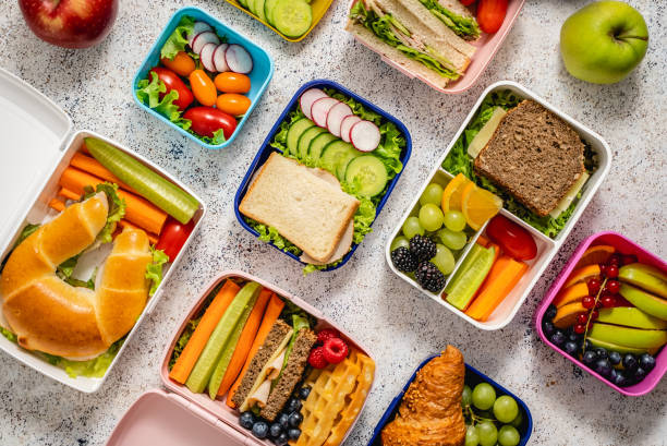Tiro de lancheiras escolares com várias refeições nutritivas saudáveis no fundo de pedra - foto de acervo