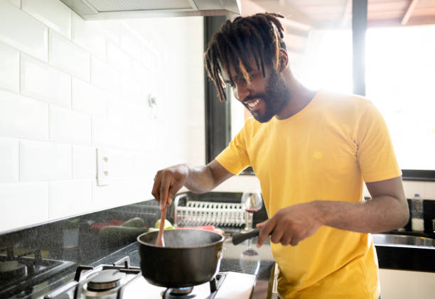 istock Smiling young man cooking sauce on his kitchen stove 1416006697