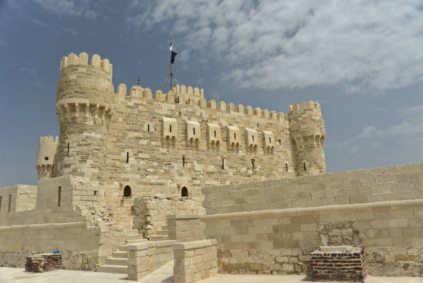 Citadel of Qaitbay, Alexandria, Egypt with the Egyptian flag on top and a background of blue cloudy sky. The Fort of Qaitbay is a 15th-century defensive fortress located on the Mediterranean sea coast stock photo