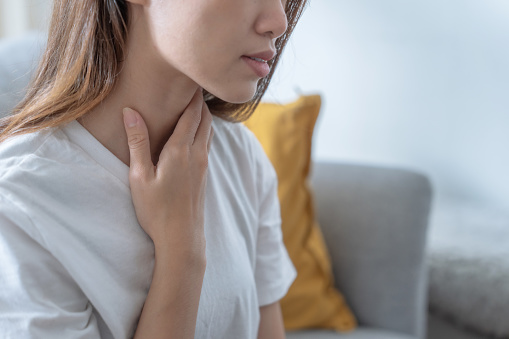 Asian woman suffering from sore throat, Acid reflux.