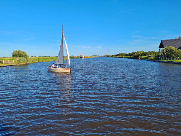 Sailing in the countryside from Friesland in the NEtherlands on a beautiful summer day Sailing in the countryside from Friesland in the NEtherlands on a beautiful summer day friesland netherlands stock pictures, royalty-free photos & images