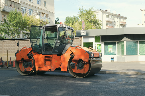 Hamm road roller HD at road works on asphalt paving. Articulated tandem vibratory roller by Hamm. Road works on improvement of city streets. Moscow, Russia - 08.13.2022