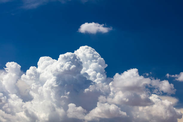 A stunning display of a towering cumulus cloud, characterized by its fluffy white appearance, set beneath a clear and serene blue sky.