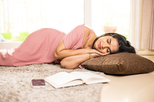 Indian young woman sleeping at floor at home.