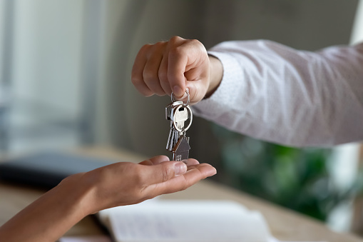 Close up professional Real estate agent giving keys to client, congratulating with purchasing own dwelling after signing contract agreement, professional real estate services, last mortgage payment concept.